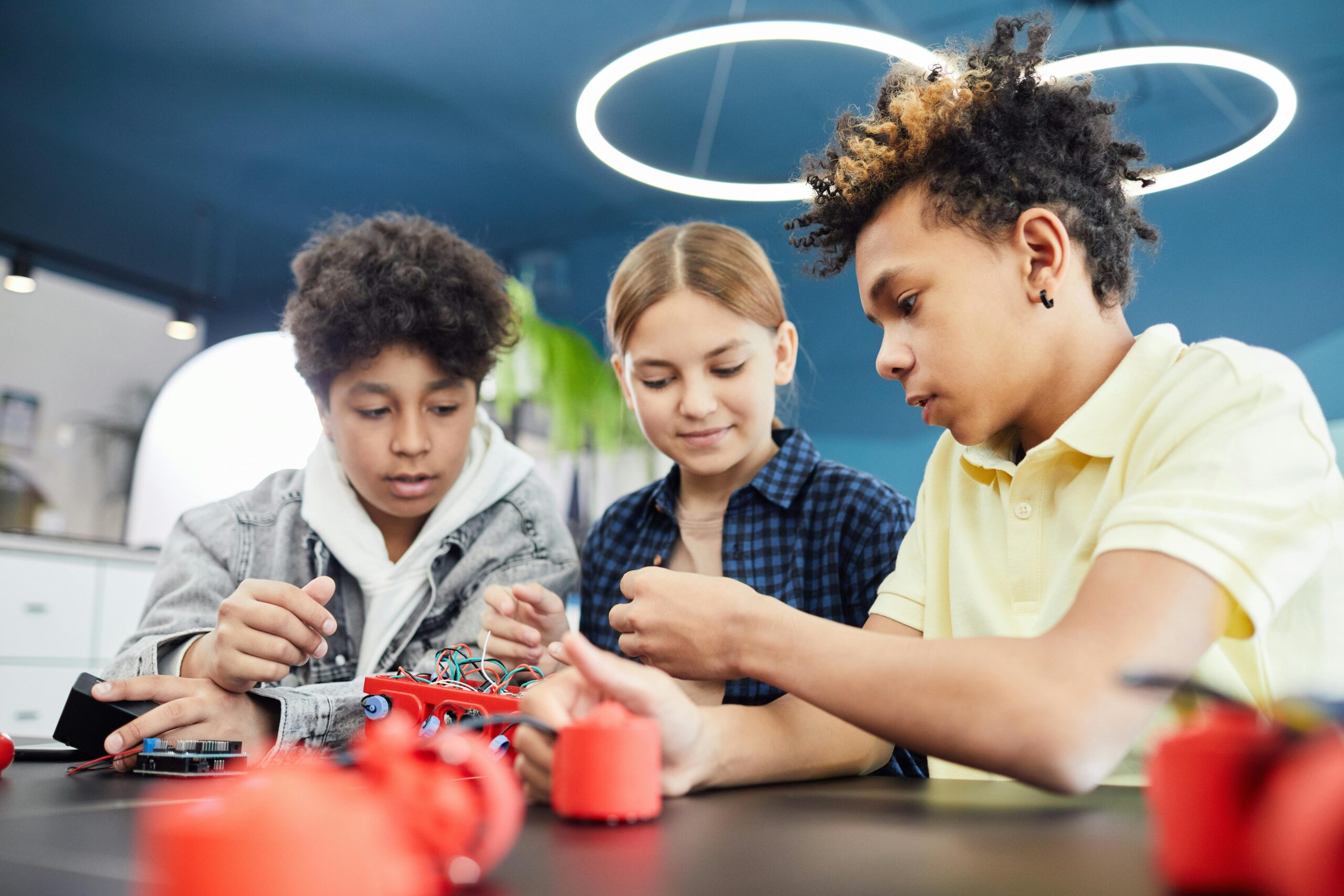Diverse teenagers collaboratively working on a robotics project in a workshop.
